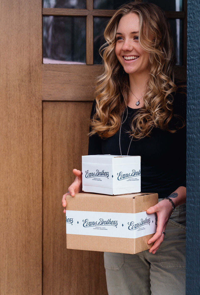 A customer holding a stack of Evans Brothers gift boxes